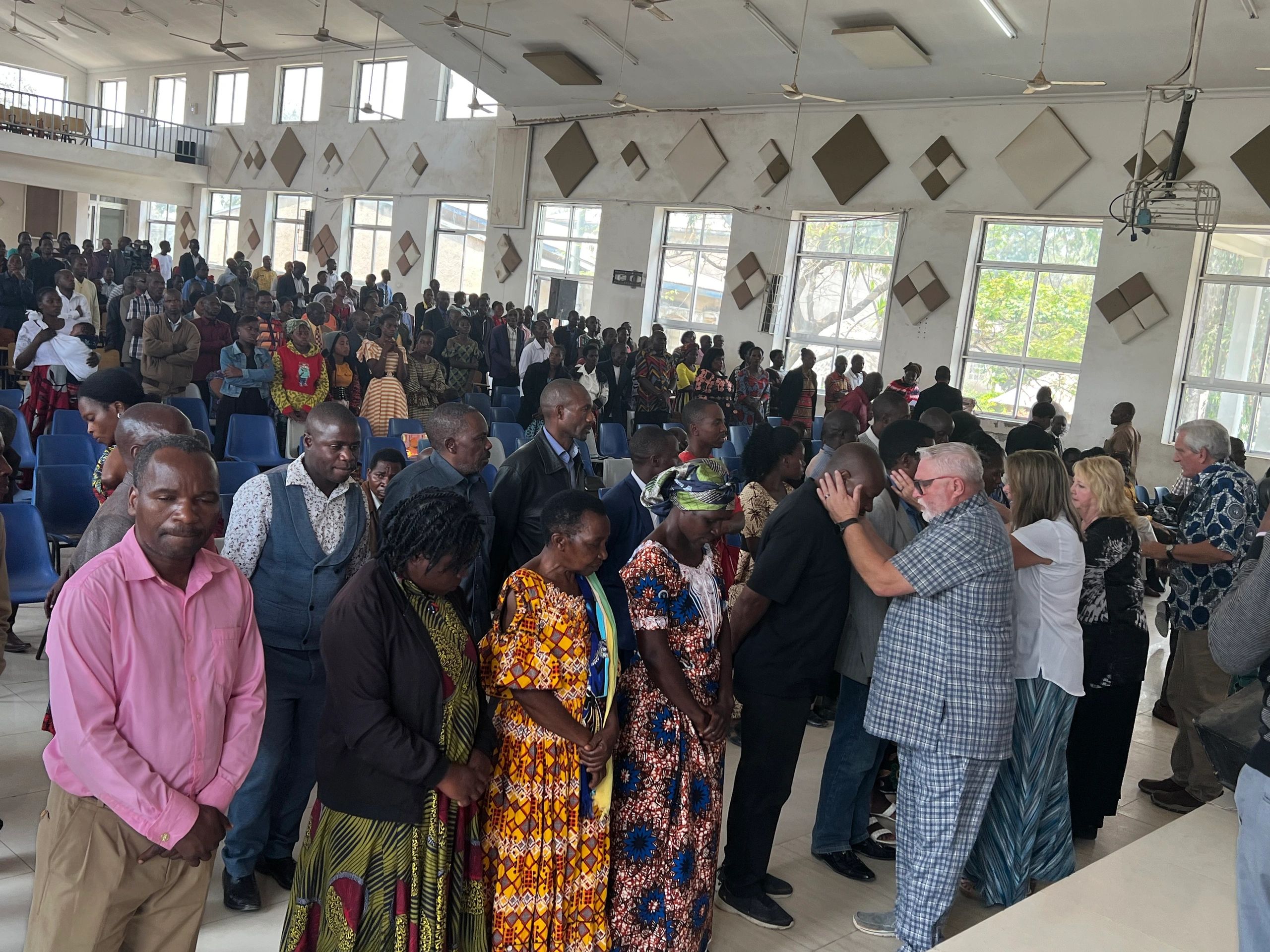 A vibrant congregation in worship as Mike Campbell prays over believers at a pastor-school gathering in Tanzania.